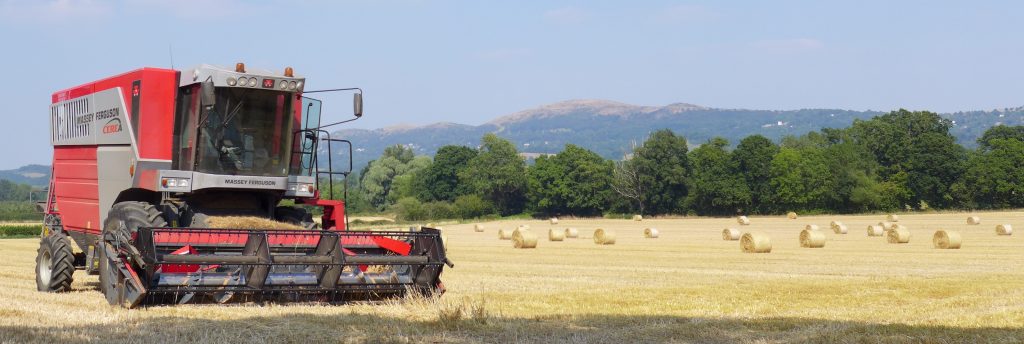 Photo of combine harvester and round bales before the Malvern Hills