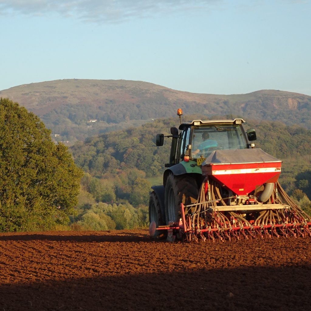 Tractor drilling seed beneath the Malvern Hills